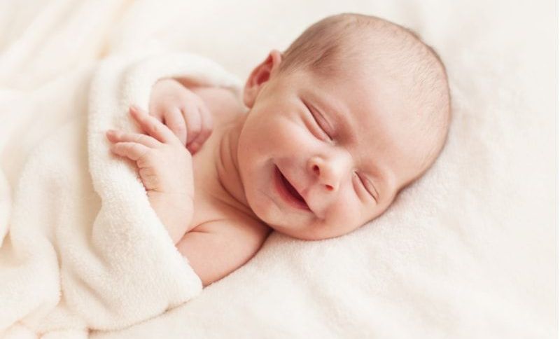schönes lächelndes Neugeborenes Baby 6 Tage alt
