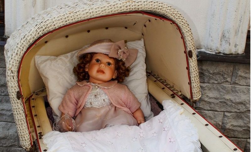 Puppenwagen aus Holz mit Puppe im Inneren
