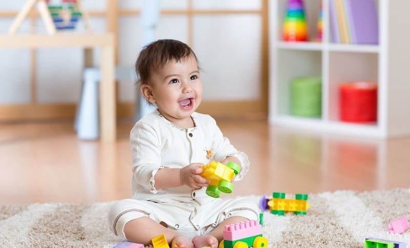 glückliches Baby spielt mit Lego-Würfeln auf dem Boden