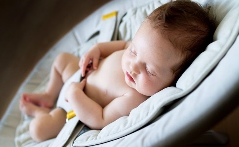 Neugeborenes Mädchen schläft in einer Schaukel im dunklen Raum
