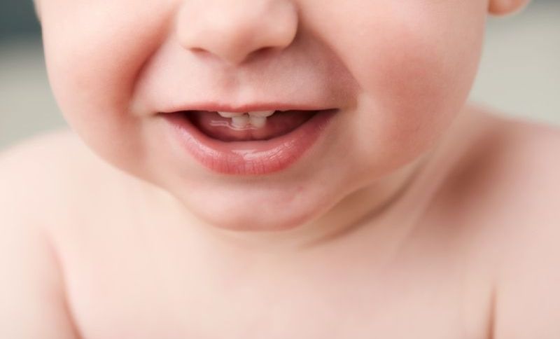 Babys offener Mund zeigt seine ersten Zähne
