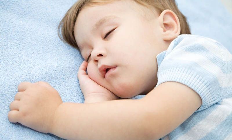 niedlichen kleinen Jungen schlafen auf dem blauen Laken und schnarchen