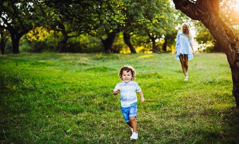 kleiner Junge läuft vor seiner Mutter im Park