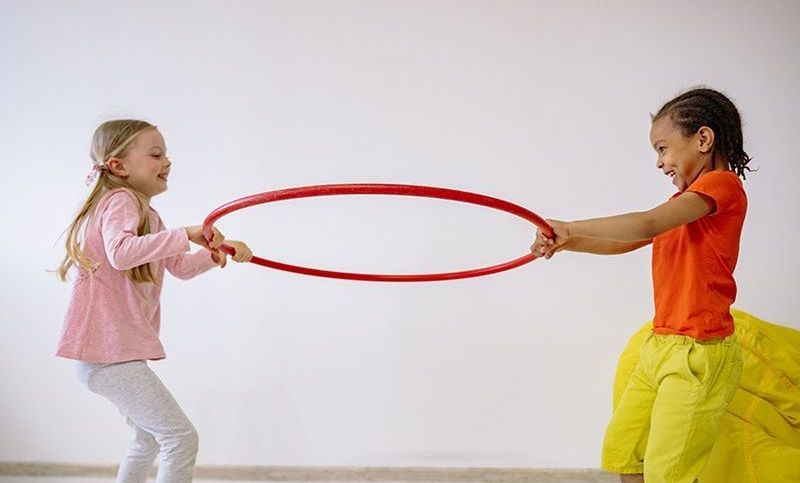 zwei Kinder, die einen Hula-Hoop-Reifen im Zimmer halten