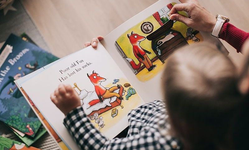 Frau liest einem kleinen Jungen ein Bilderbuch vor