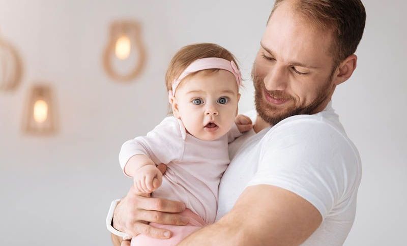 lächelnd Vater hält ihre süße Baby-Tochter in rosa Pyjama