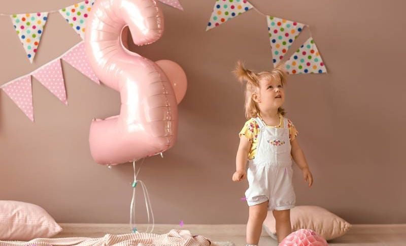 Nettes kleines Mädchen in einem für eine Geburtstagsparty dekorierten Zimmer