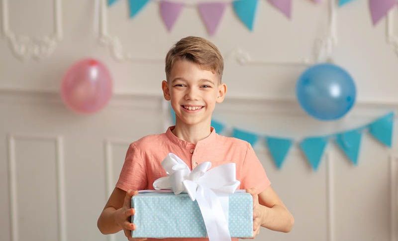 lächelnd niedlichen Jungen hält ein Geburtstagsgeschenk