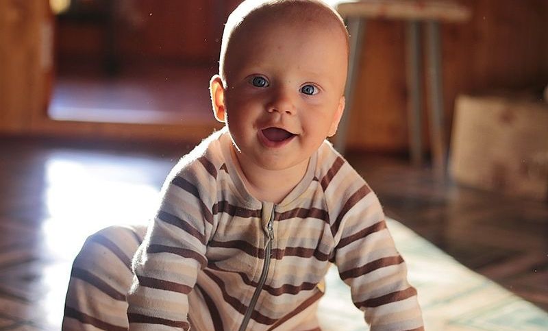 Baby Junge sitzt auf dem Boden und lächelt