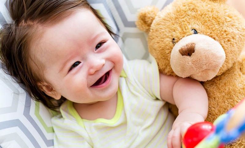 süßes Baby lächelnd und liegend mit Teddybär