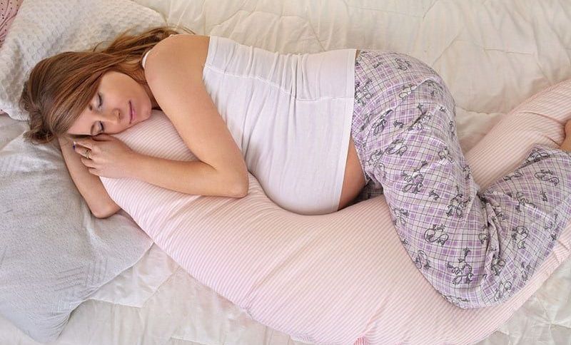 schwangere Frau, die auf Schwangerschaftskissen schläft