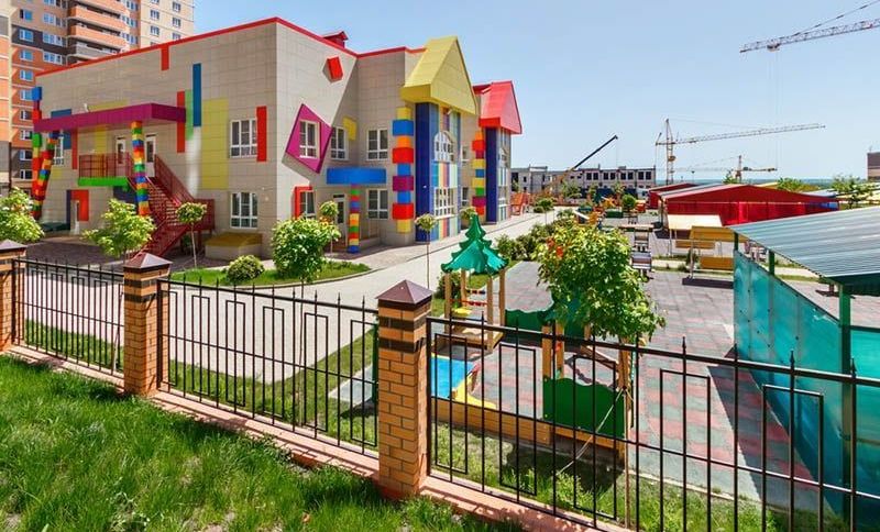 buntes Kindergartengebäude mit Spielplätzen im Hof