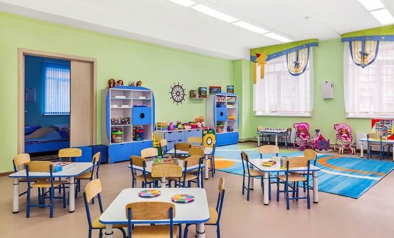 Kindergartenraum voller Tische und Stühle für Kinder und Spiele