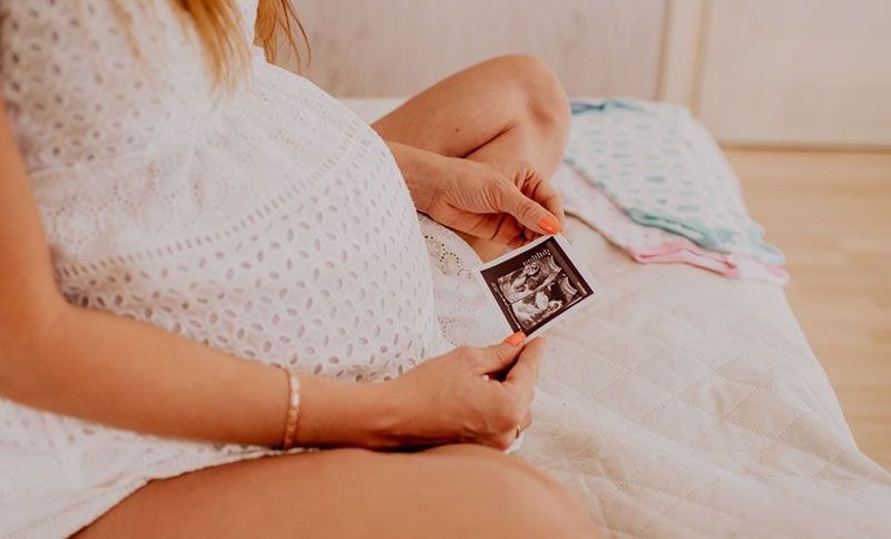 die schwangere Frau, die Ultraschallbild von Babyzwillingen betrachtet